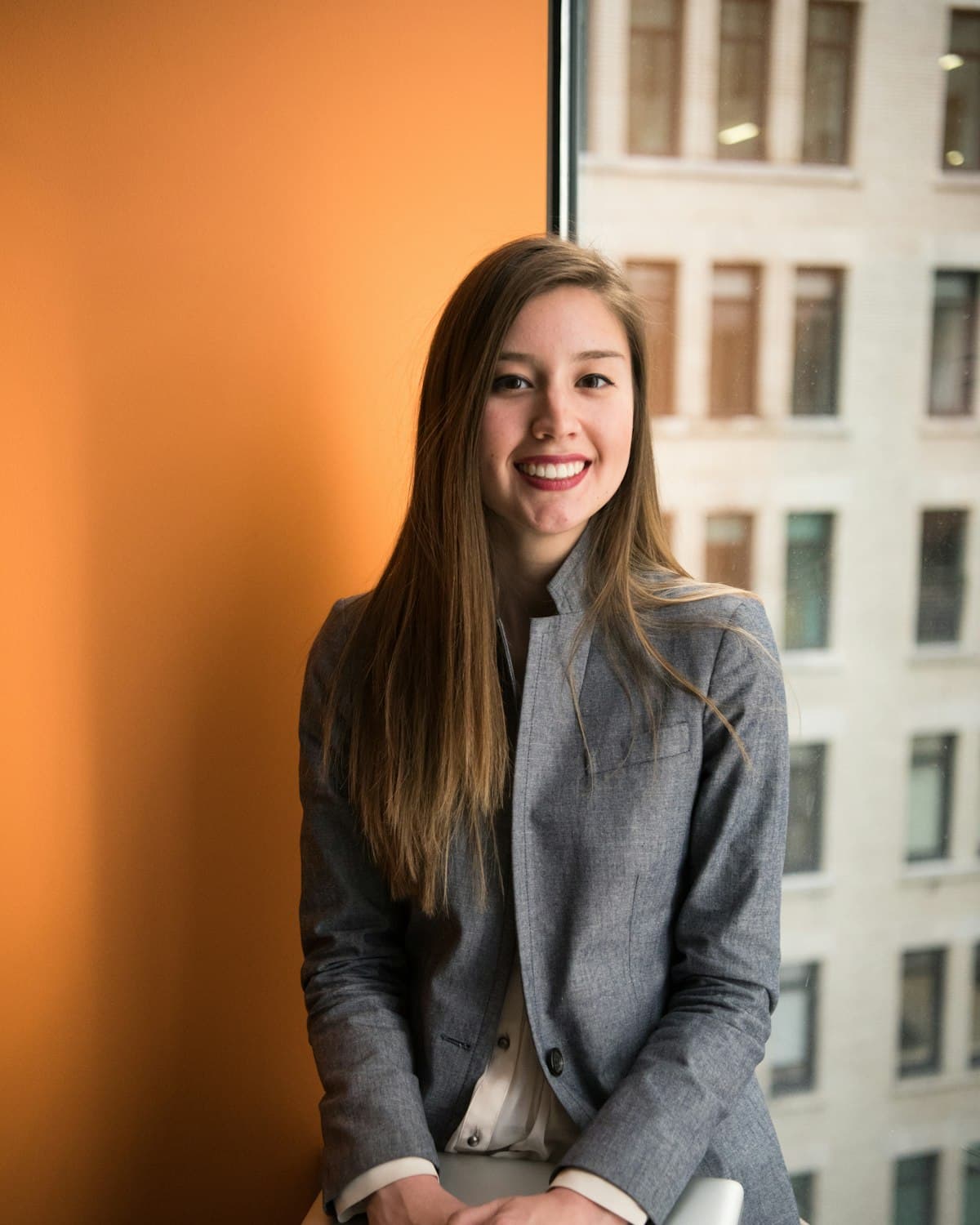 A consultant in a blazer smiling with her laptop in a modern office